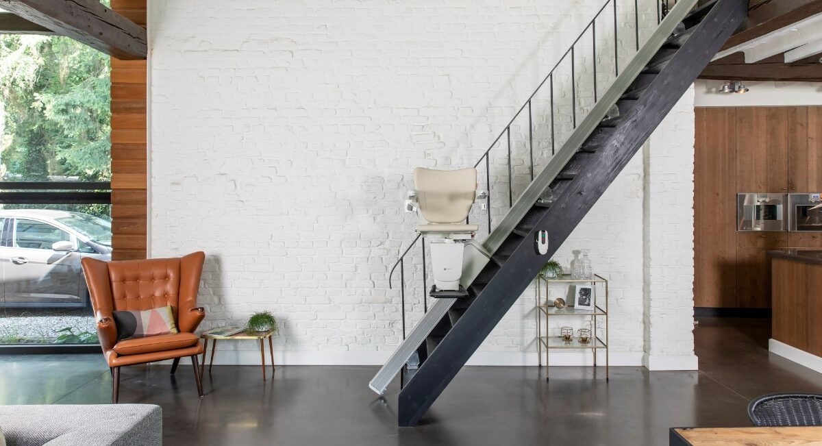 Das Bild zeigt eine modern eingerichtete Wohnung im Loft-Stil. Eine steile Metalltreppe führt auf eine Galerie. Ein Treppenlift ist fahrbereit.