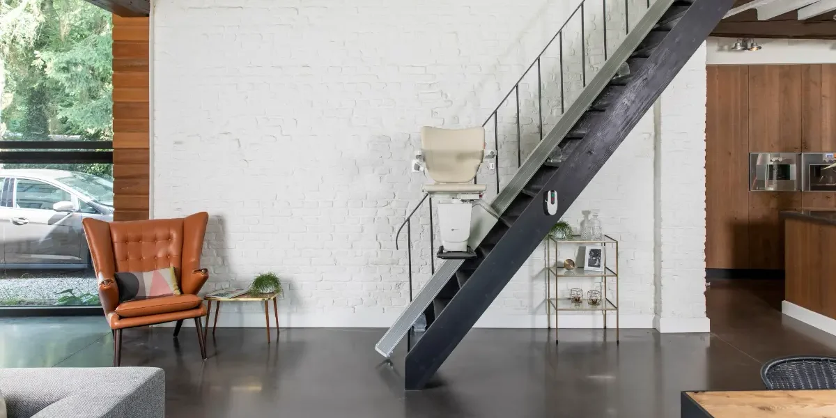 Das Bild zeigt eine modern eingerichtete Wohnung im Loft-Stil. Eine steile Metalltreppe führt auf eine Galerie. Ein Treppenlift ist fahrbereit.