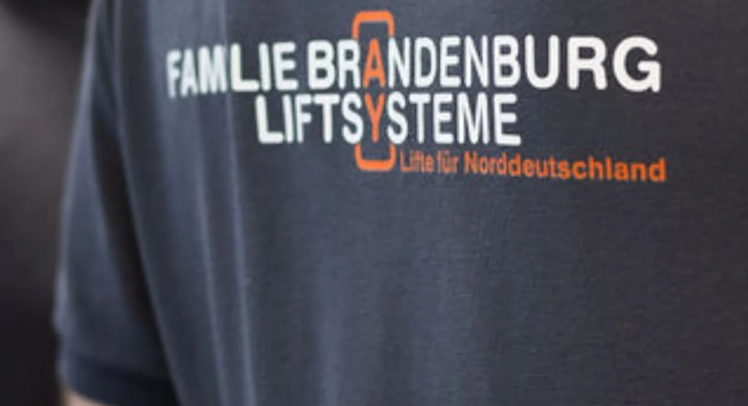 Das Bild zeigt die Rückseite eines Polohemdes mit dem Logo der Firma Brandenburg.