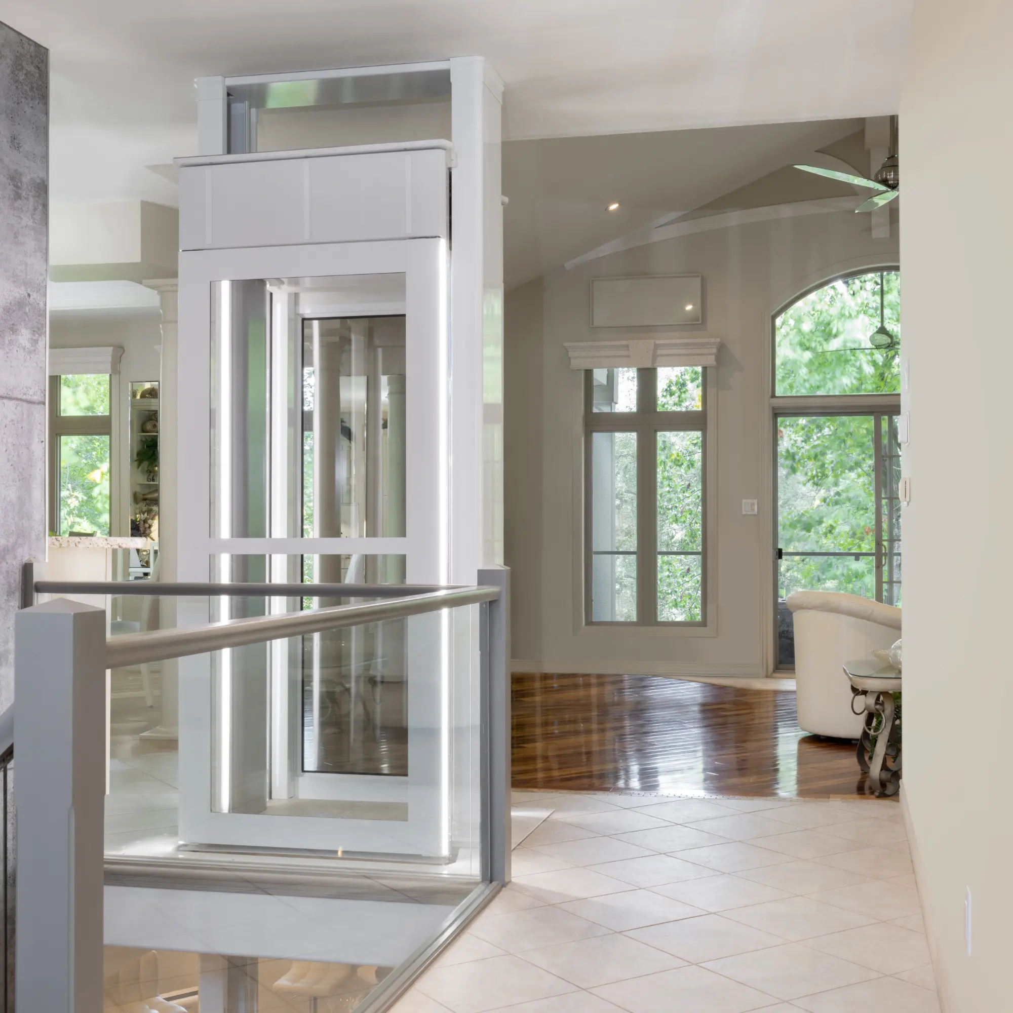 Das Bild zeigt die obere Haltestelle eines Luma-Senkrechtliftes inkl. Fahrstuhlkabine voneinem Standort aus, der hinter dem Fahrstuhl liegt. Sehr gut erkennbar sind die Glaselemente und die lichtdurchflutete Kabine.